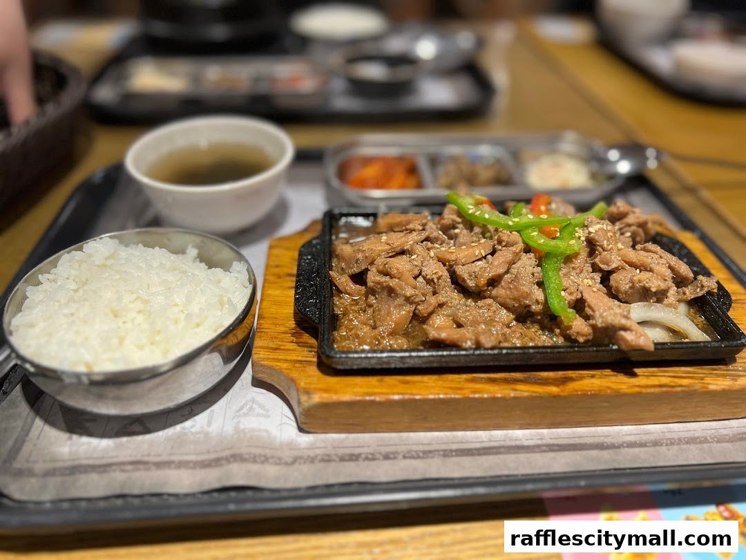 A sizzling Korean bulgogi dish served with rice and side dishes.