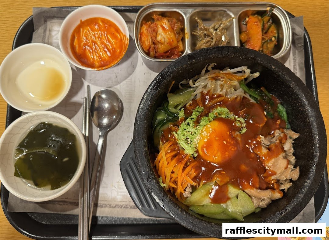 A delicious Korean bibimbap served with various side dishes and a bowl of soup.