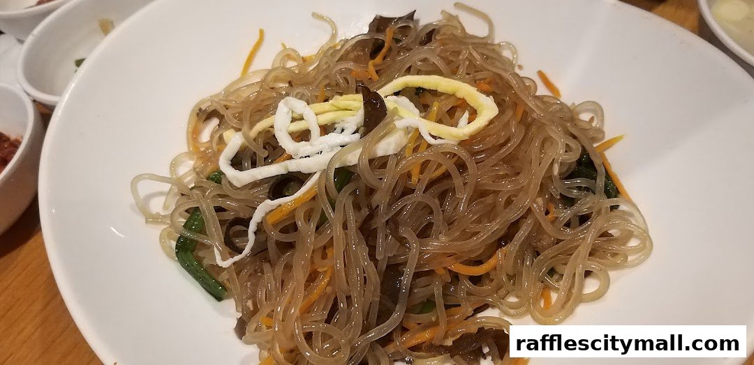 A close-up shot of a delicious plate of Japchae, a Korean glass noodle dish.