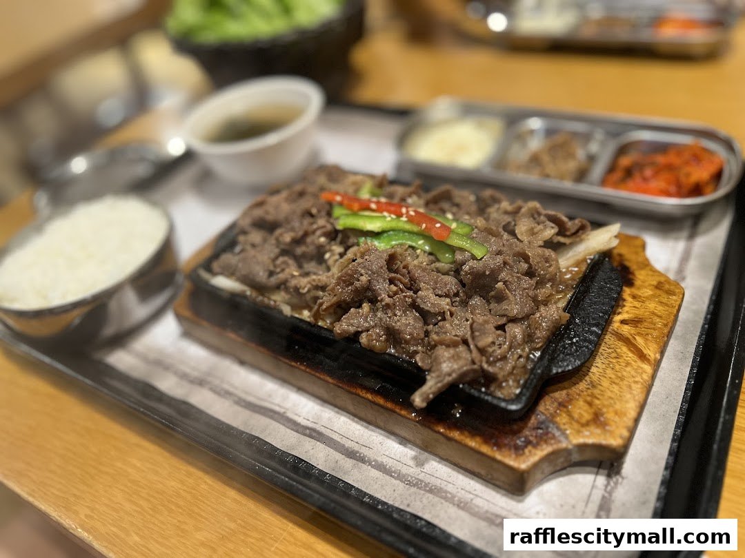 A sizzling plate of Korean bulgogi with rice and side dishes.