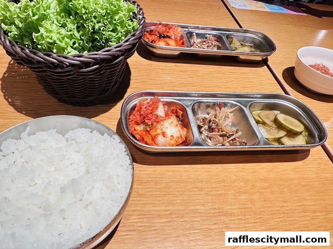 A table setting at a Korean restaurant with rice, kimchi, pickles, and lettuce.