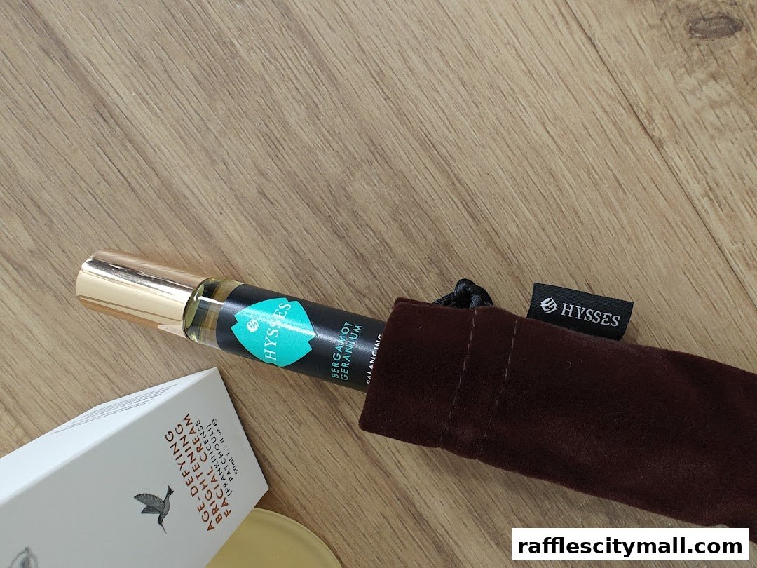 A HYSSES rollerball perfume and a box of facial cream on a wooden surface.