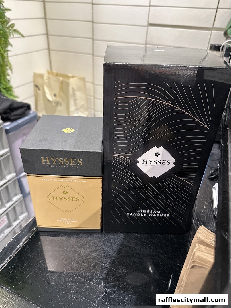 Two HYSSES branded products, a candle and a candle warmer, are displayed on a counter.