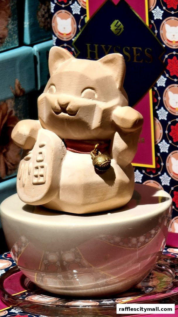 A decorative ceramic cat figurine with a bell sits on a bowl, with shop branding in the background.