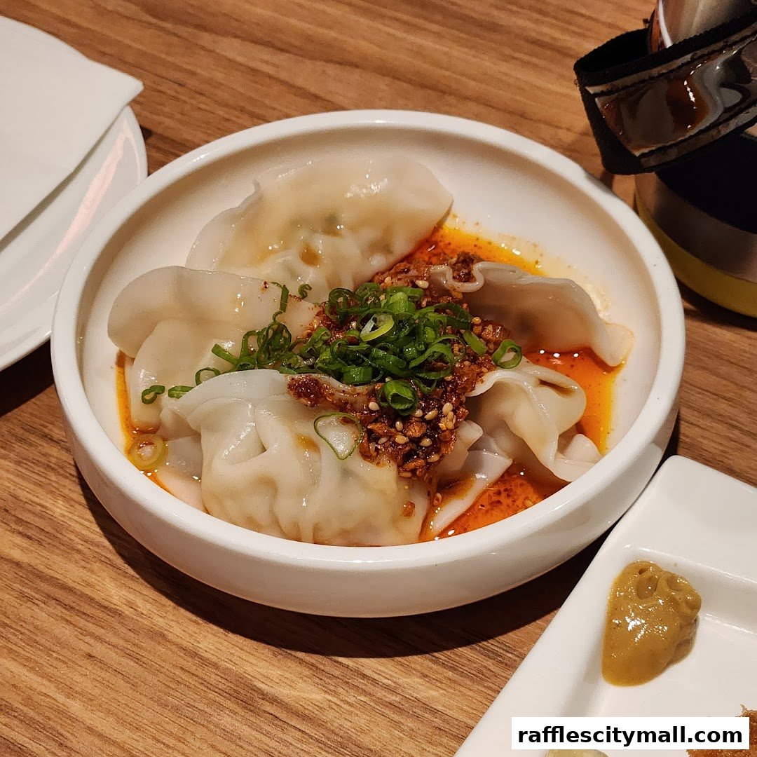 A bowl of delicious dumplings with chili oil and green onions, served at a restaurant.