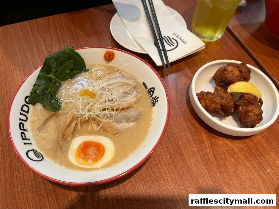 A bowl of ramen with chicken karaage and a drink on a wooden table.