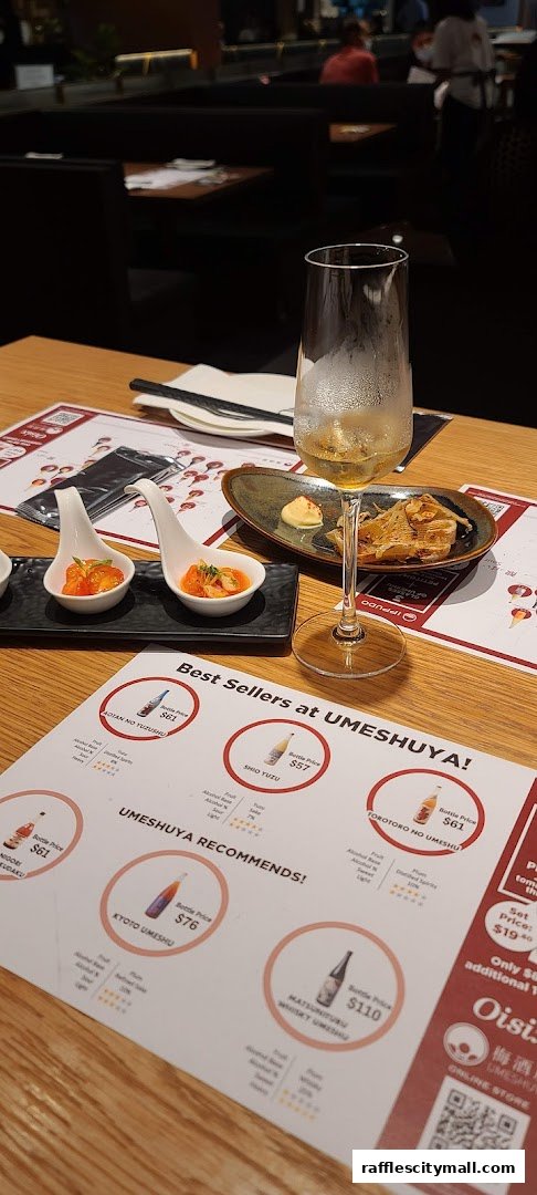 A table setting at Umesuya with appetizers, a glass of wine, and a menu featuring best sellers.