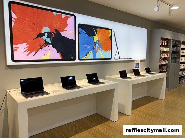 Modern tech store interior showcasing Apple laptops and large display screens with vibrant artwork.