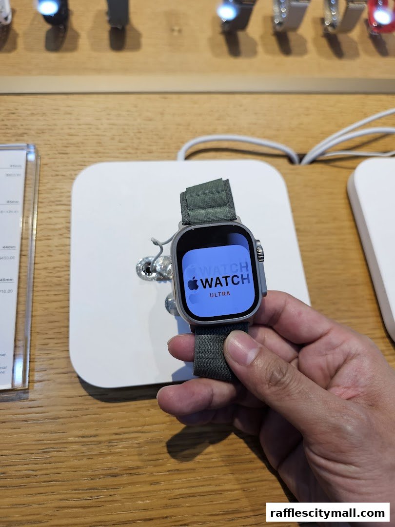 A hand holds an Apple Watch Ultra with a green band on display.