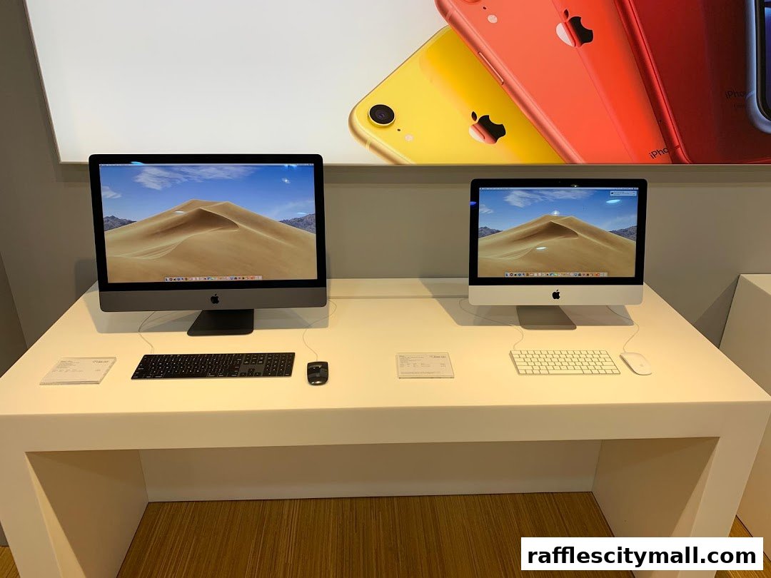 Two iMac computers are displayed on a white counter with Apple keyboards and mice.