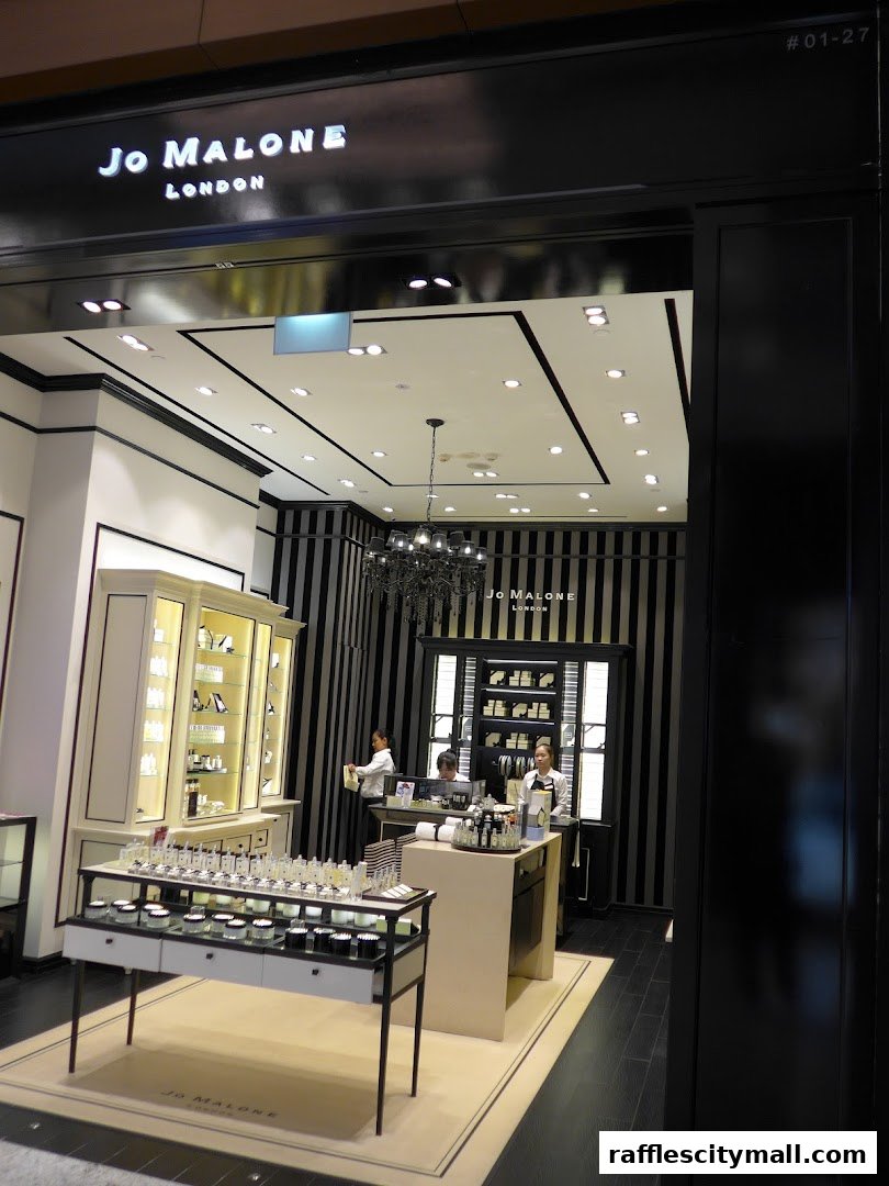 The entrance of a Jo Malone London store with displays of perfumes and staff members.