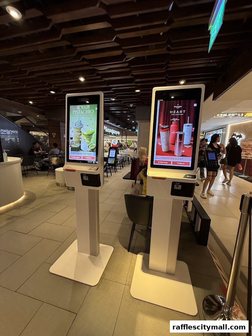Two digital kiosks display promotions for Kenangan Coffee's Royale Pistachio and Heart Collection.