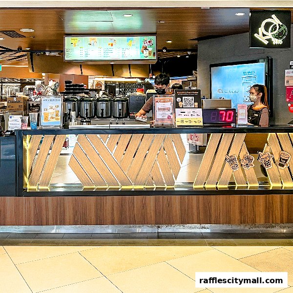 Staff serving customers at the KOI Thé Express counter with a menu board above.
