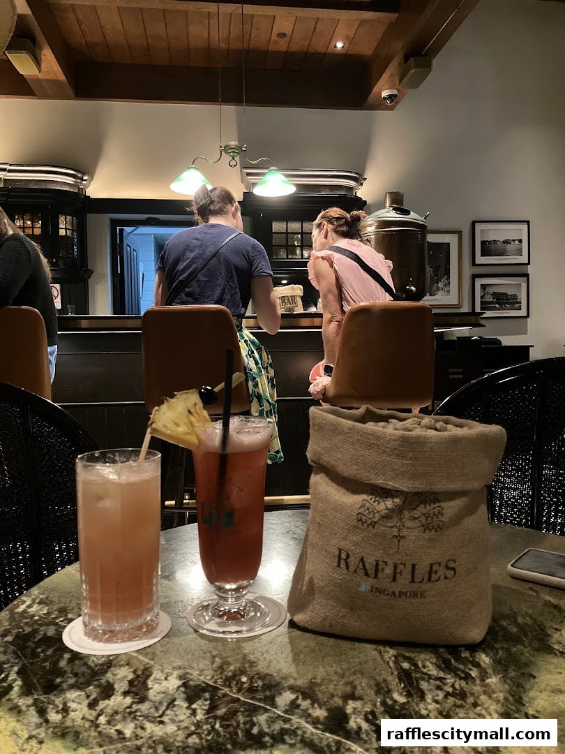 Two people sit at a bar with cocktails and a burlap bag on the table.