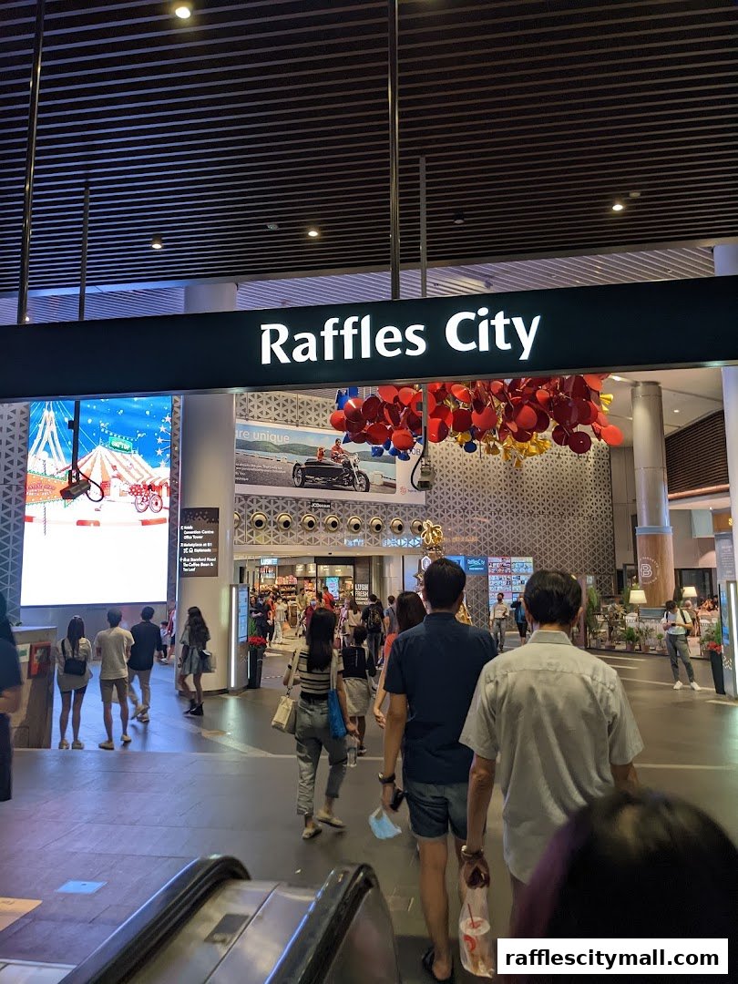 People walking in Raffles City mall with a large sign and festive decorations.