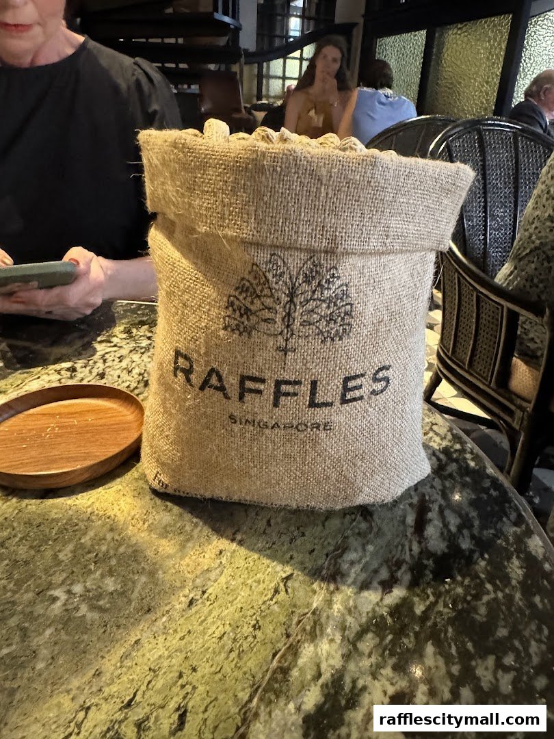 A burlap sack with the Raffles Singapore logo sits on a marble table.