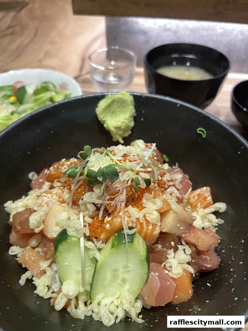 A close-up of a colorful Chirashi bowl with fresh sashimi, cucumber, and roe, served with miso soup.