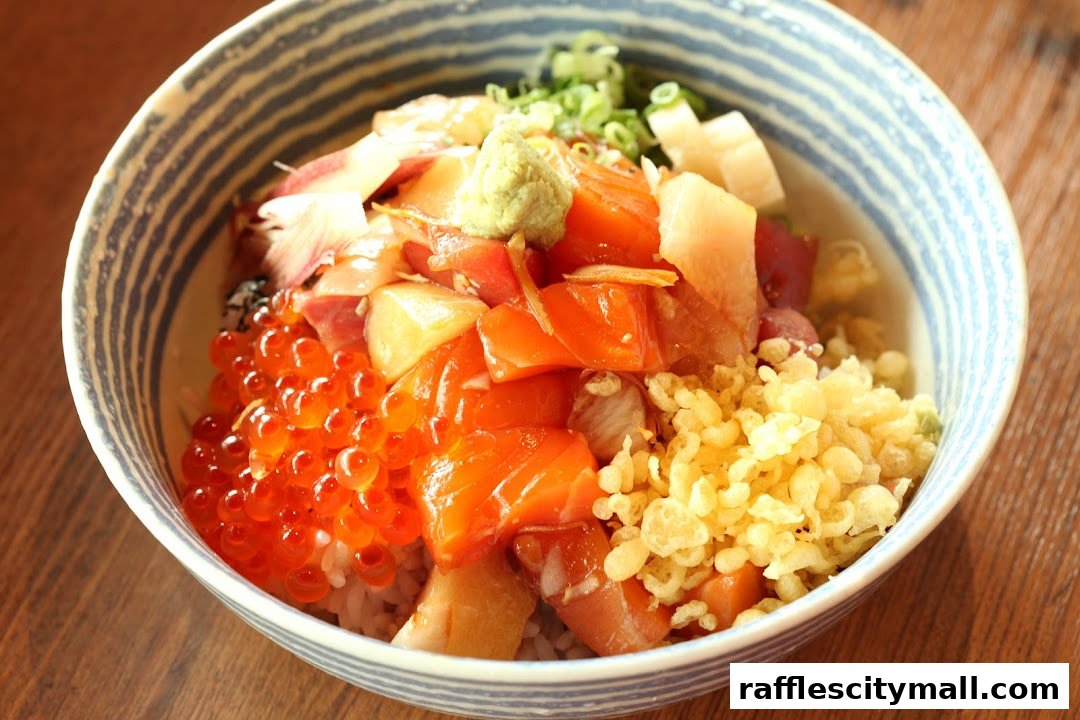 A close-up of a colorful Chirashi bowl filled with fresh sashimi, ikura, and tempura bits.