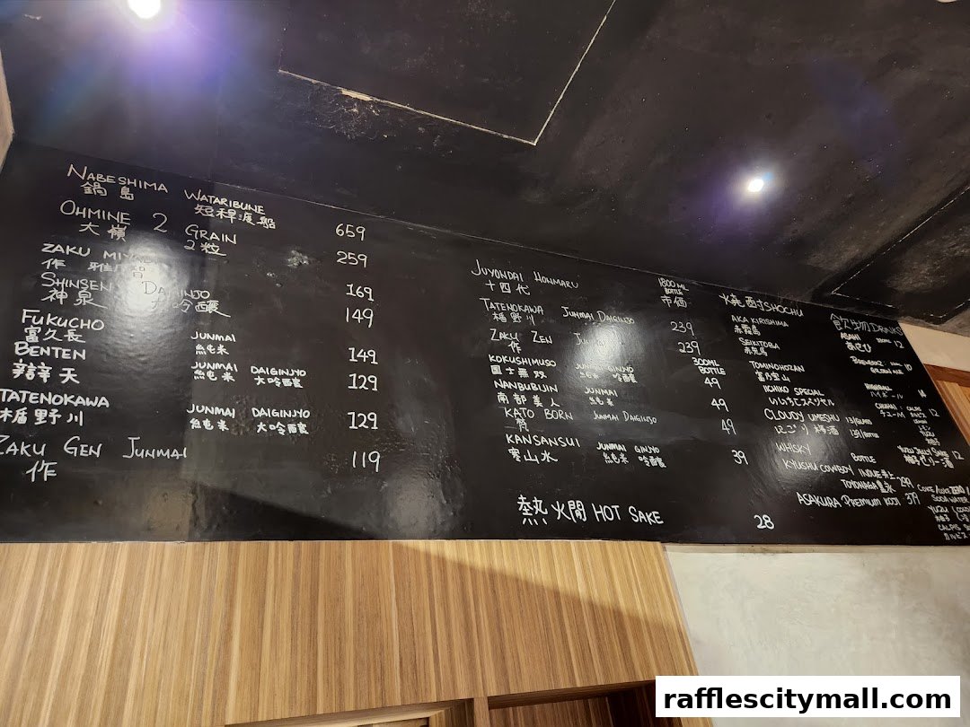 A black chalkboard menu displaying various Japanese sake and drinks with prices.