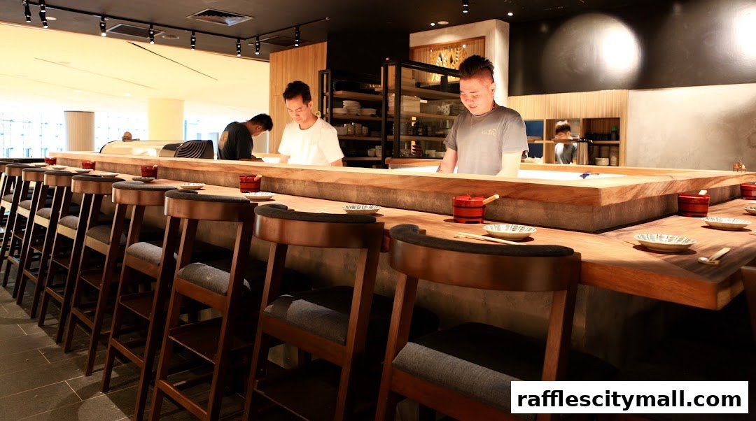 Chefs preparing food behind a sushi bar with seating for customers.