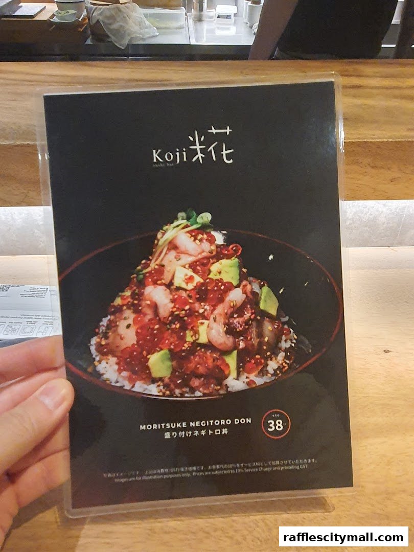 A menu item from Koji Sushi Bar featuring a bowl of rice topped with negitoro, shrimp, and avocado.