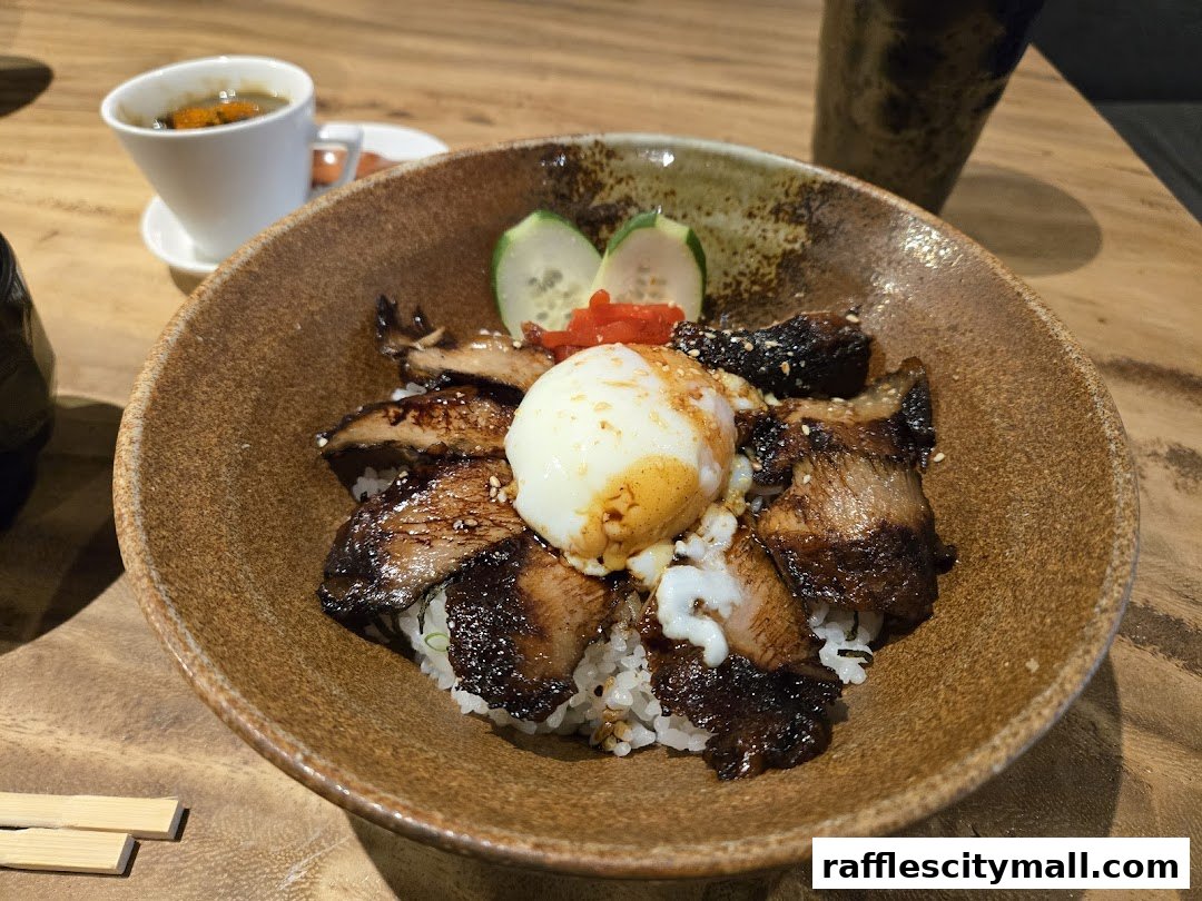 A delicious bowl of Japanese rice with grilled meat and a soft-boiled egg, served with a side of soup.