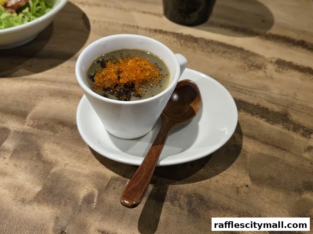 A close-up of a white cup filled with a creamy dish topped with orange roe and dark toppings.