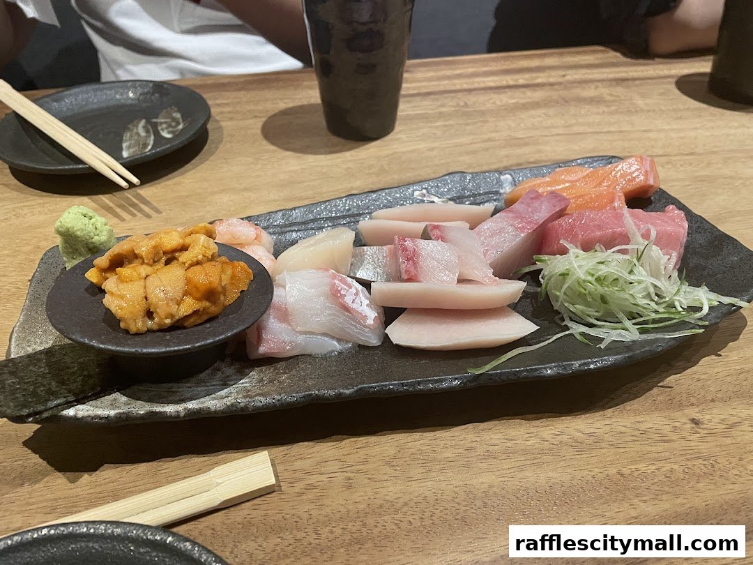 A platter of assorted sashimi, including uni, salmon, tuna, and white fish, served with wasabi.