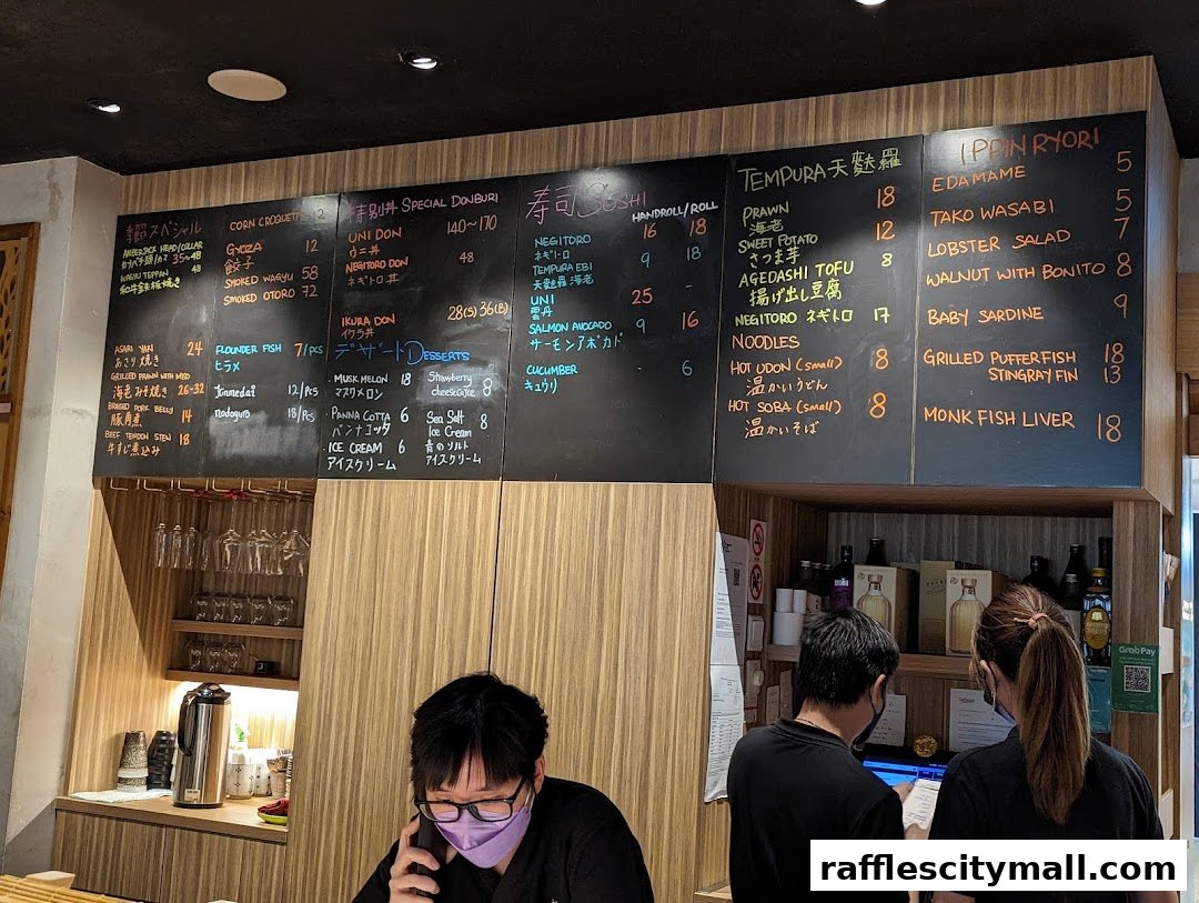 A chalk menu board displaying various Japanese dishes and prices at Koji Sushi Bar.
