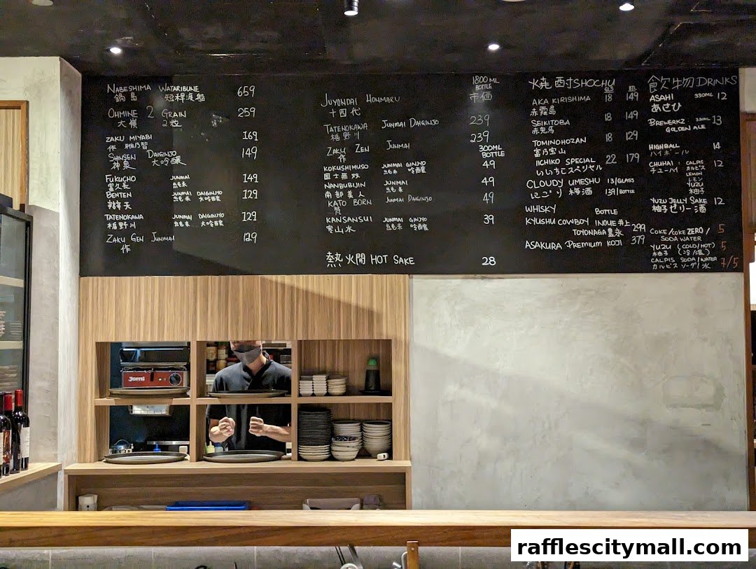 A blackboard menu at Koji Sushi Bar displays various Japanese sakes, shochu, whisky, and drinks with prices.