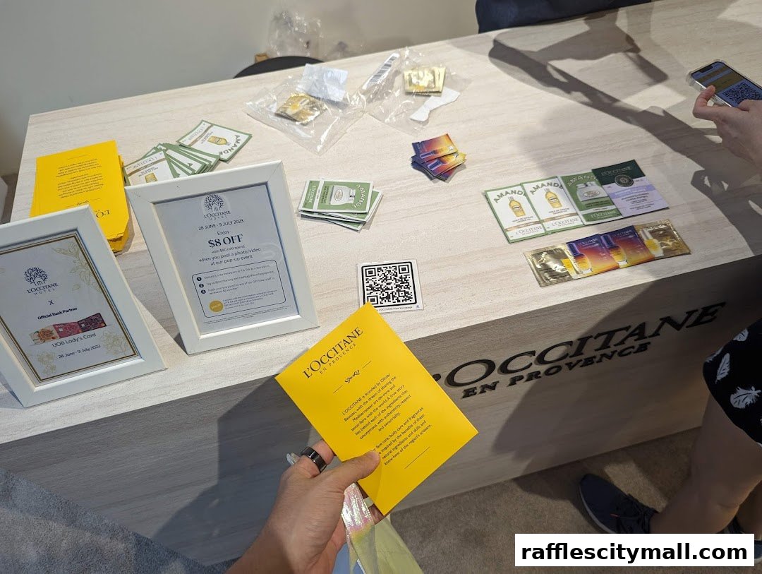 A display table at L'OCCITANE featuring promotional flyers, sample sachets, and QR codes.