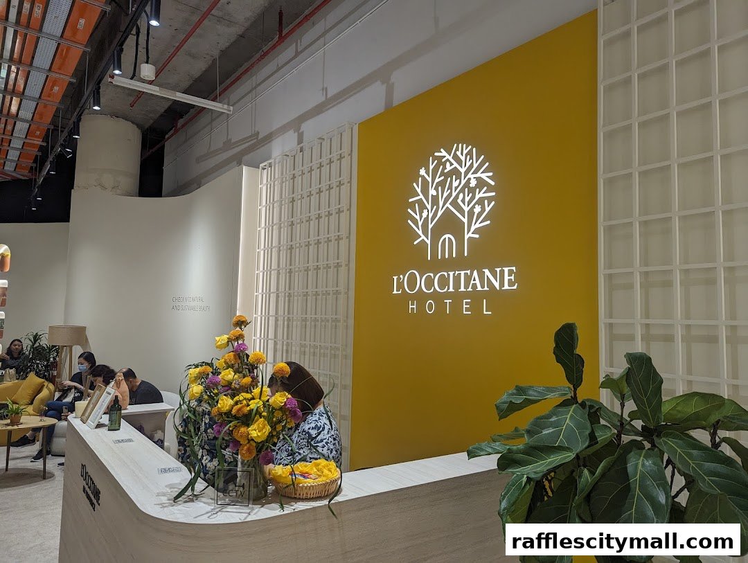 The L'Occitane Hotel reception area with a bright yellow wall and floral arrangements.