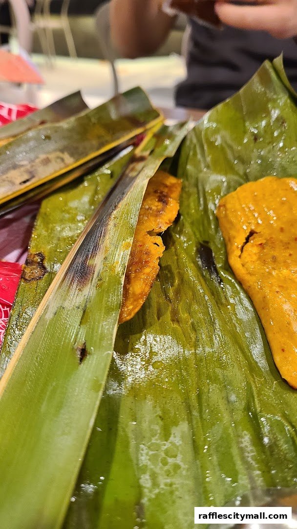 Close-up of delicious food items wrapped in banana leaves, showcasing their vibrant colors.