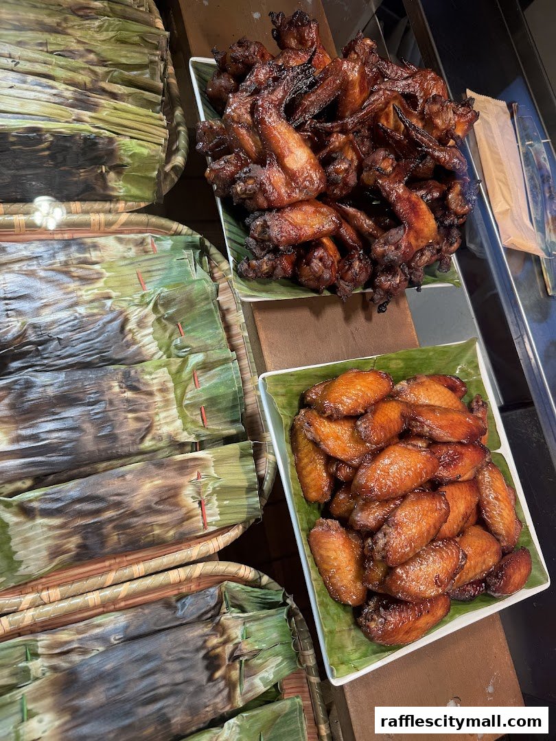 A close-up view of delicious grilled chicken wings and food items wrapped in banana leaves.