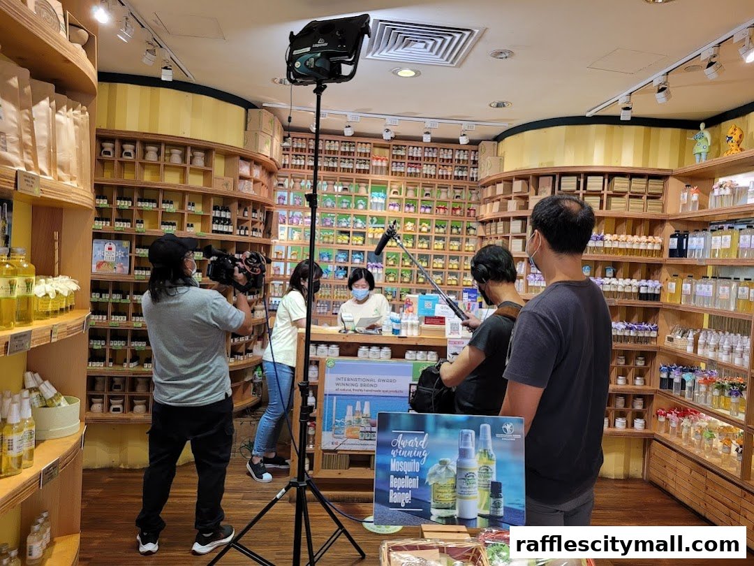 A film crew records a demonstration inside a Lemongrass House shop filled with products.