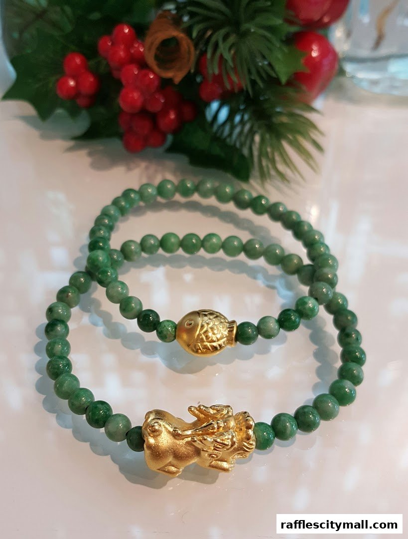 Two jade bracelets with gold charms, one a fish and the other a mythical creature.