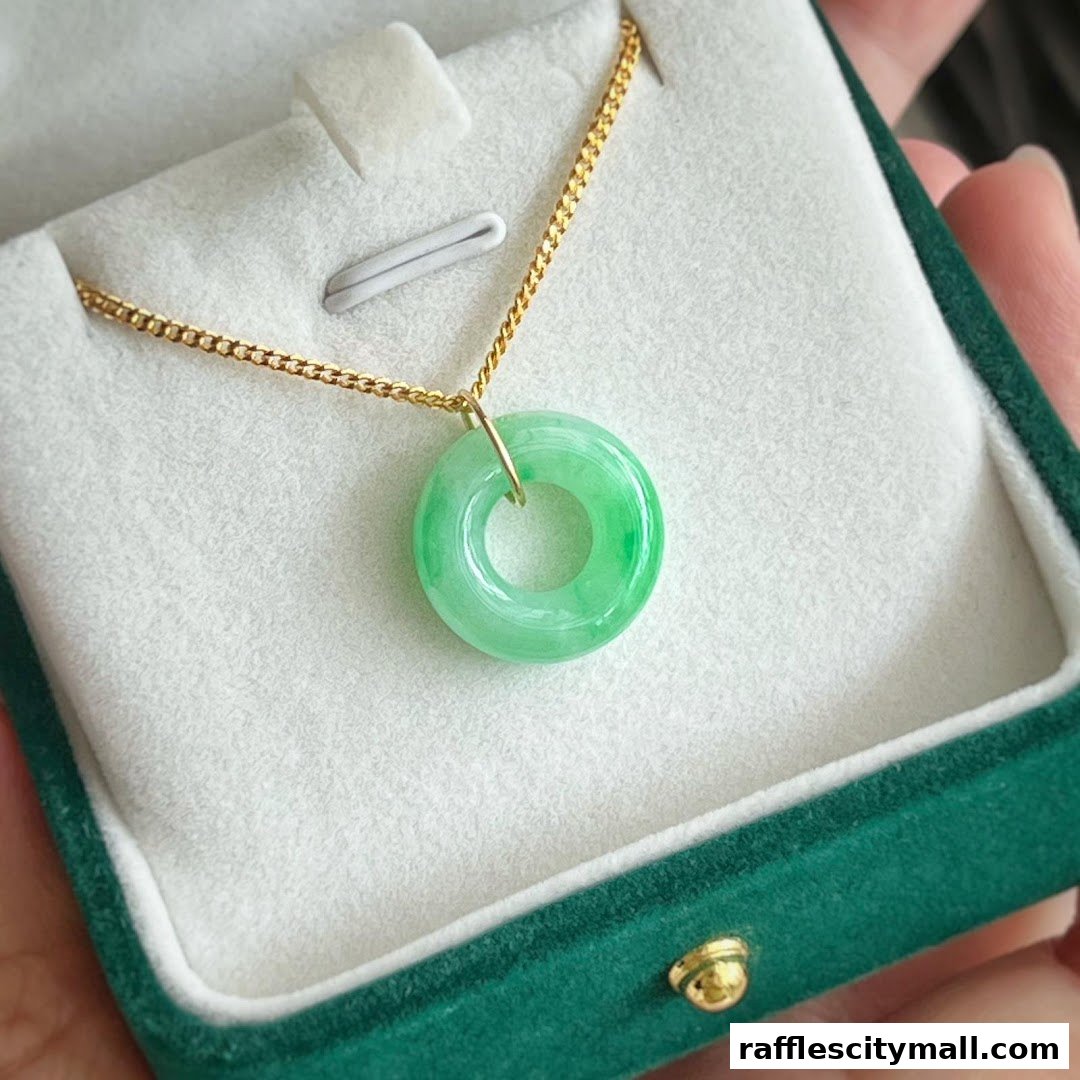 A close-up of a green jade pendant on a gold chain in a jewelry box.