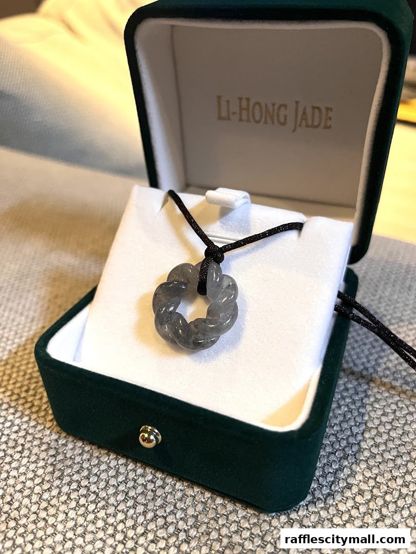 A jade pendant in a jewelry box with the shop name Li-Hong Jade.