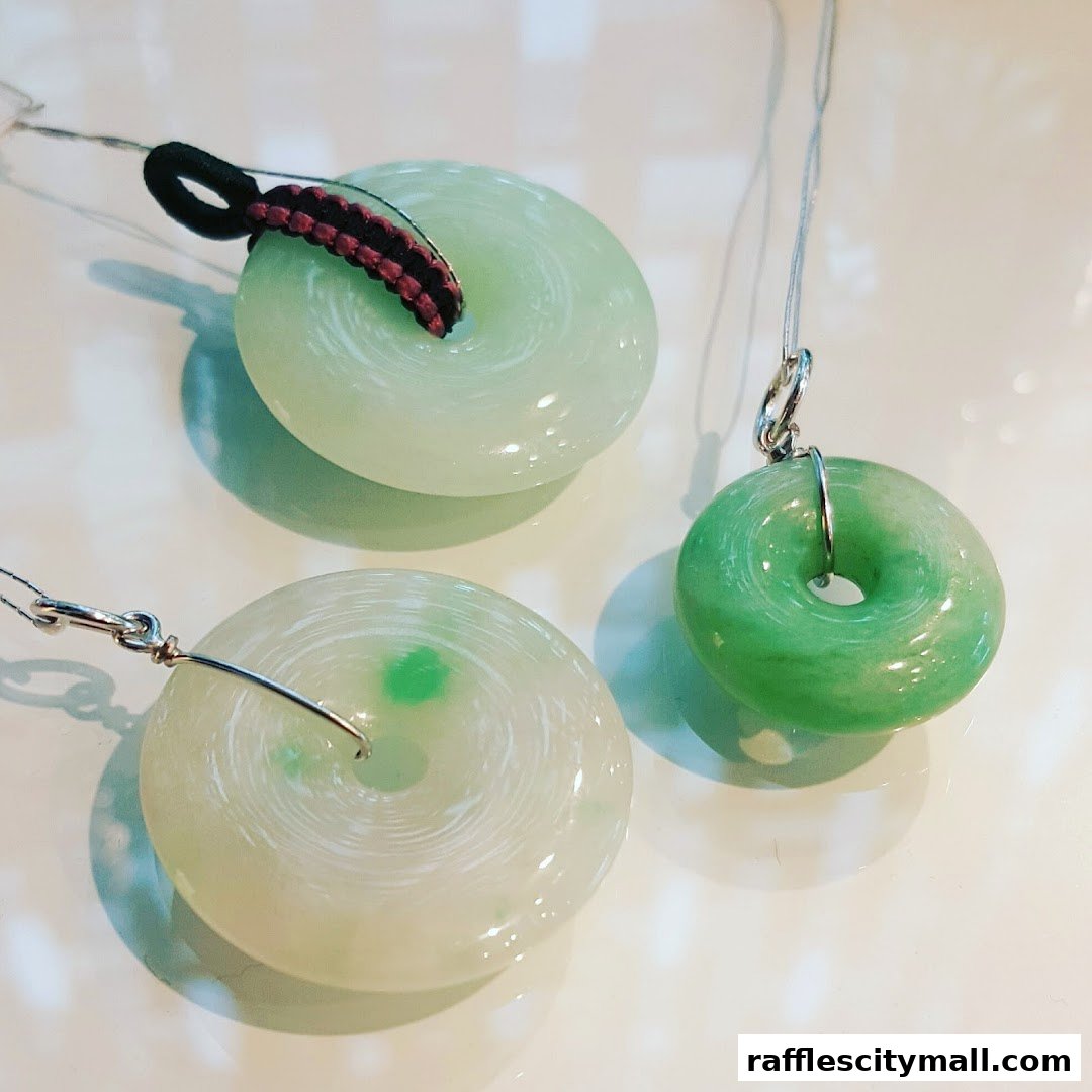 Three circular jade pendants with varying shades of green and white.