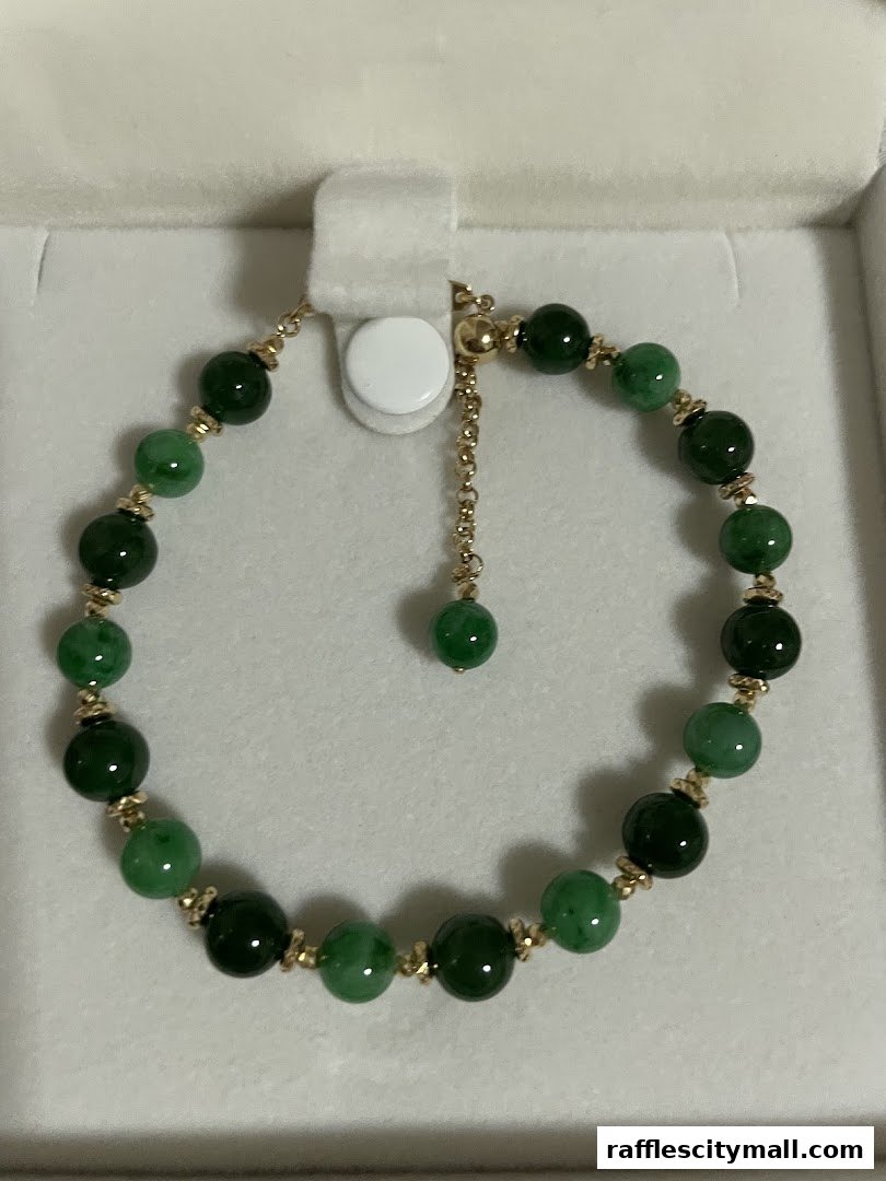 A close-up of a jade beaded bracelet with gold accents, presented in a white box.