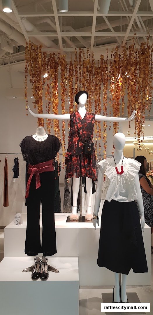 Mannequins display stylish outfits with a decorative floral garland hanging from the ceiling.