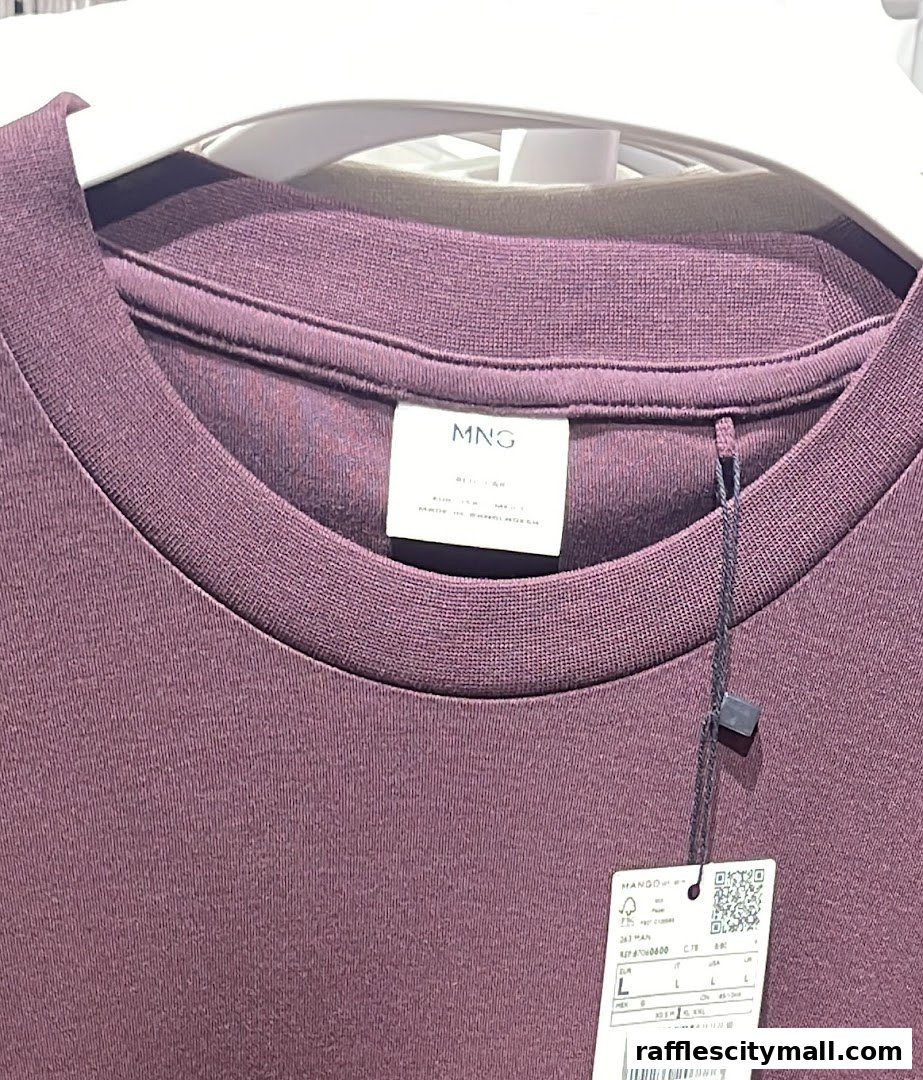 Close-up of a purple MANGO t-shirt with a label and price tag attached.