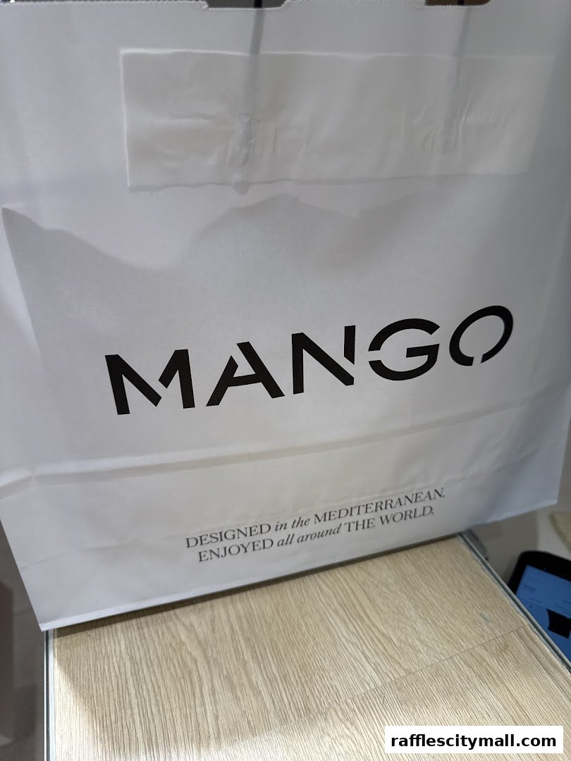 A white shopping bag with the MANGO logo and a tagline about Mediterranean design.