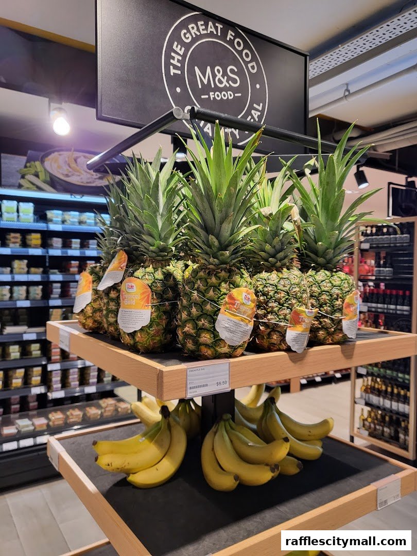 Fresh pineapples and bananas displayed on shelves at a Marks & Spencer food store.