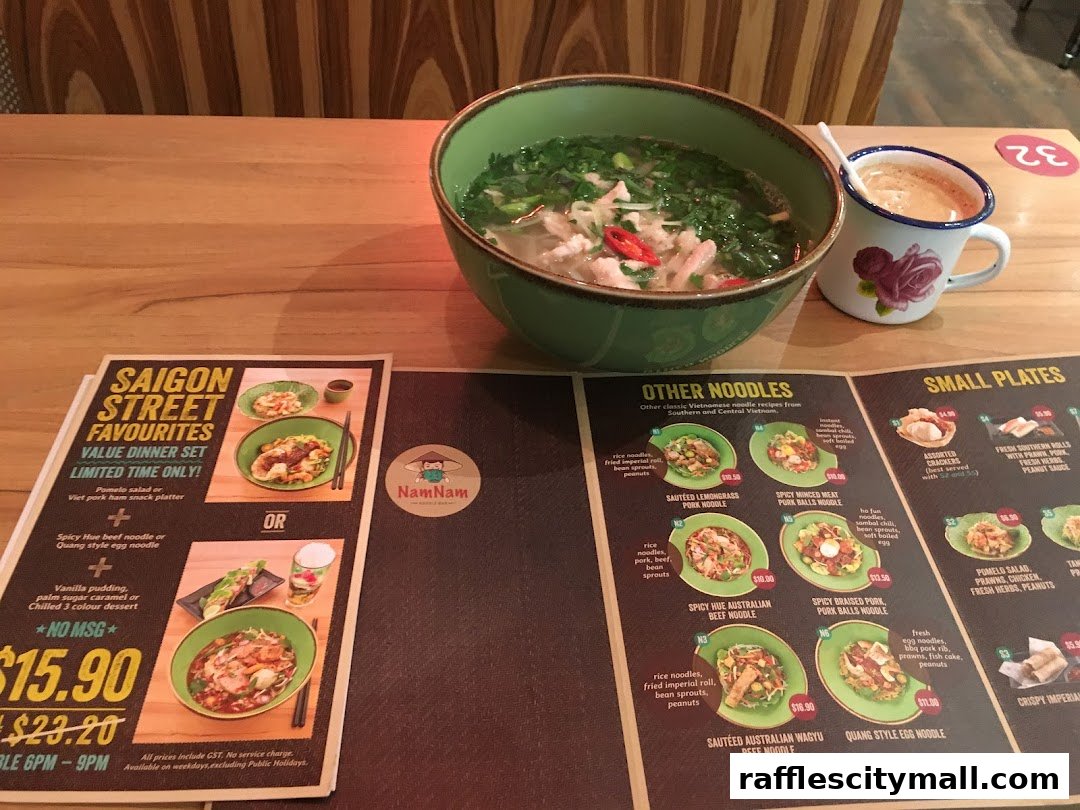 A Vietnamese restaurant menu featuring noodle dishes and small plates, with a bowl of pho and a drink.