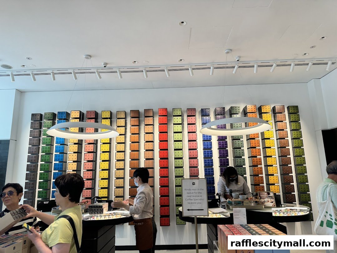 Customers are served at a Nespresso boutique with a wall display of coffee capsules.