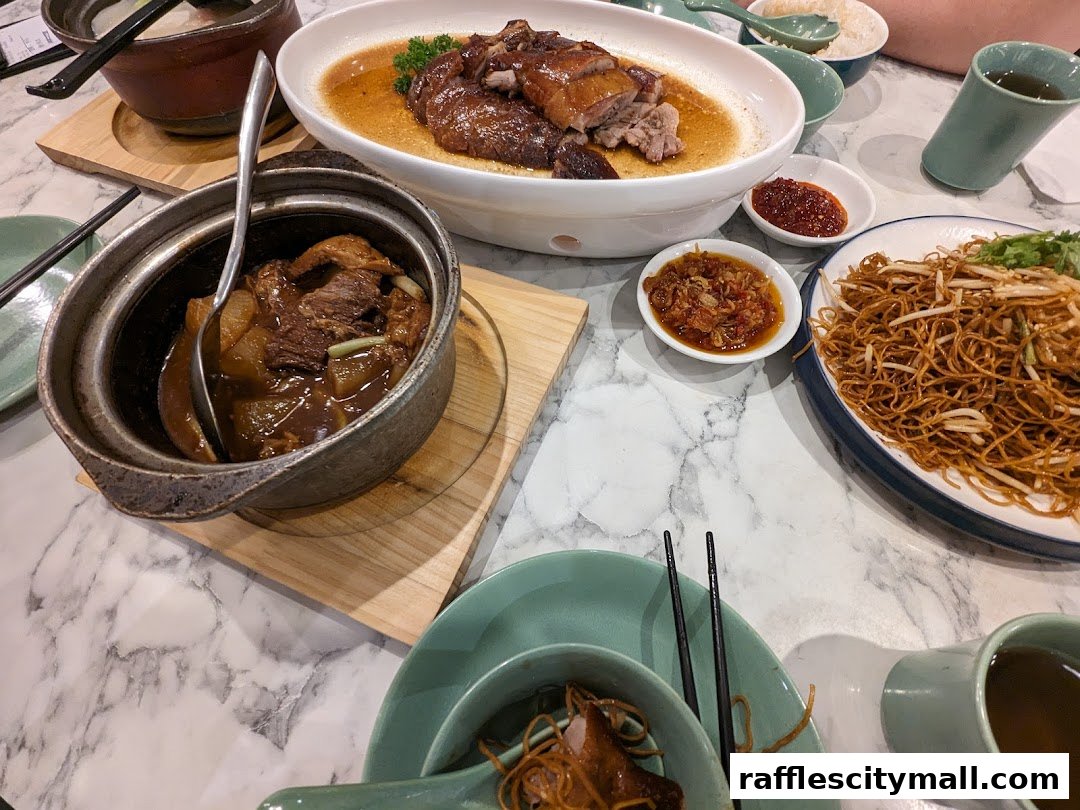 A table laden with delicious Chinese dishes, including braised meat, roasted duck, and fried noodles.
