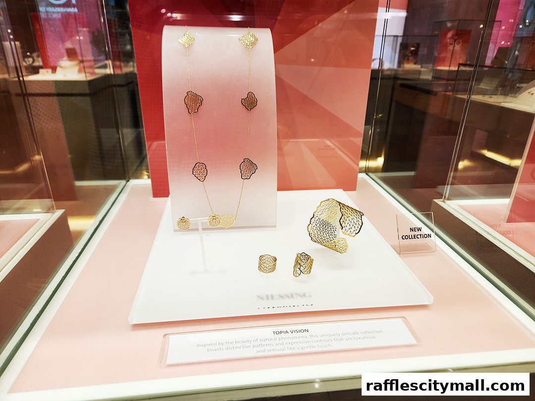 A display of gold jewelry, including a necklace, bracelet, and rings, in a shop window.