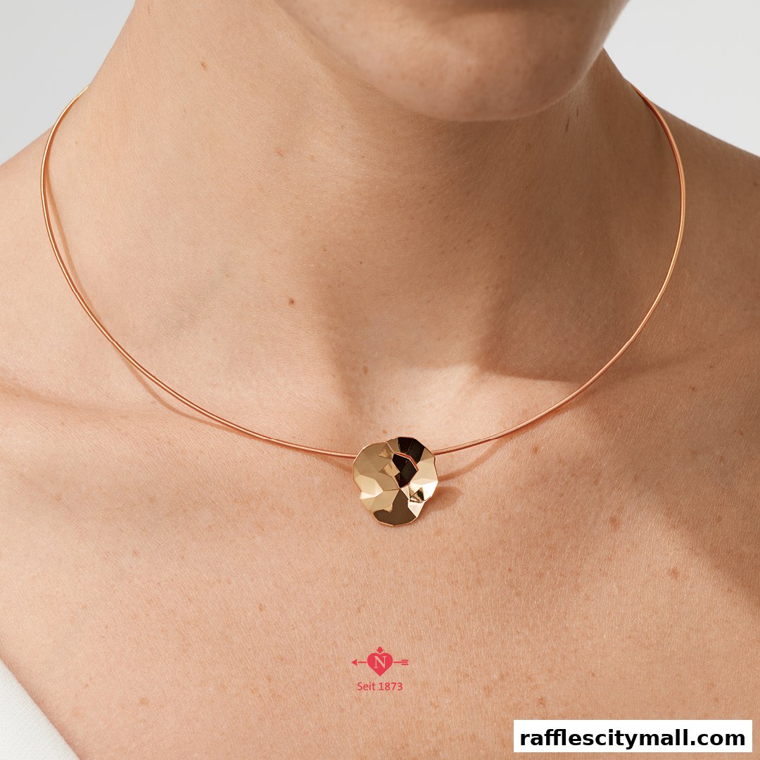 A close-up shot of a person wearing a gold pendant necklace with a thin gold chain.