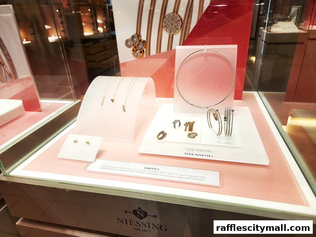A jewelry display case featuring necklaces, earrings, rings, and bracelets from Niessing.